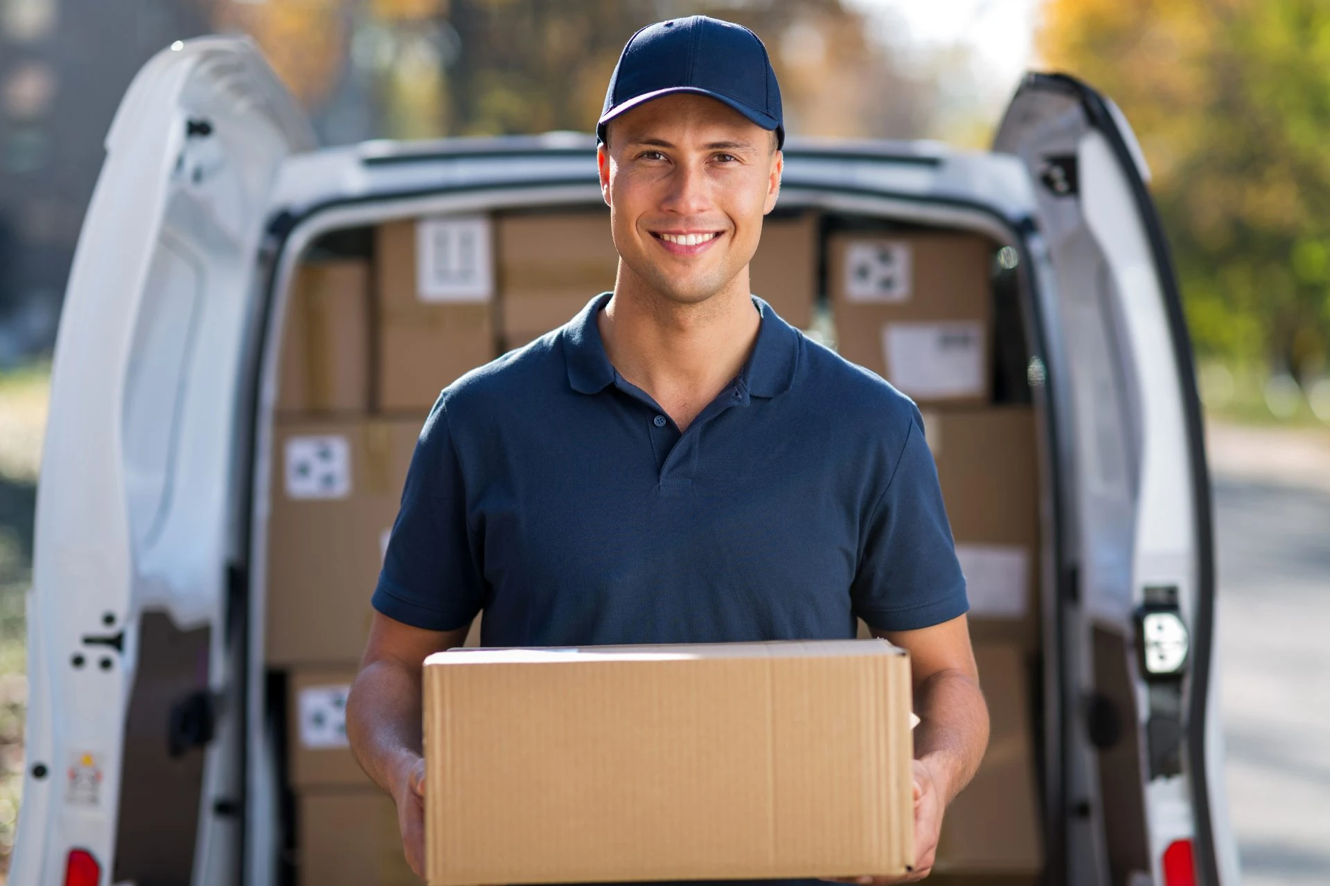 Trained delivery driver holding a parcel at the back of a van
